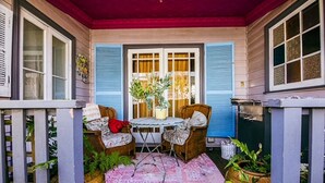 Un portico con due poltrone in vimini, un tavolino rotondo e un tappeto rosa decorato.