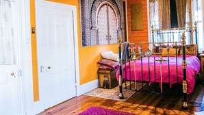 Una camera da letto con un letto, un pavimento in legno, una porta bianca e una finestra con tende.
