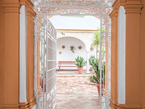 An open gate leading to a courtyard with a bench, potted plants, and decorative wall elements. - Dreams of the Jewish Quarter * Oasis in Carmona Seville * (Carmona)