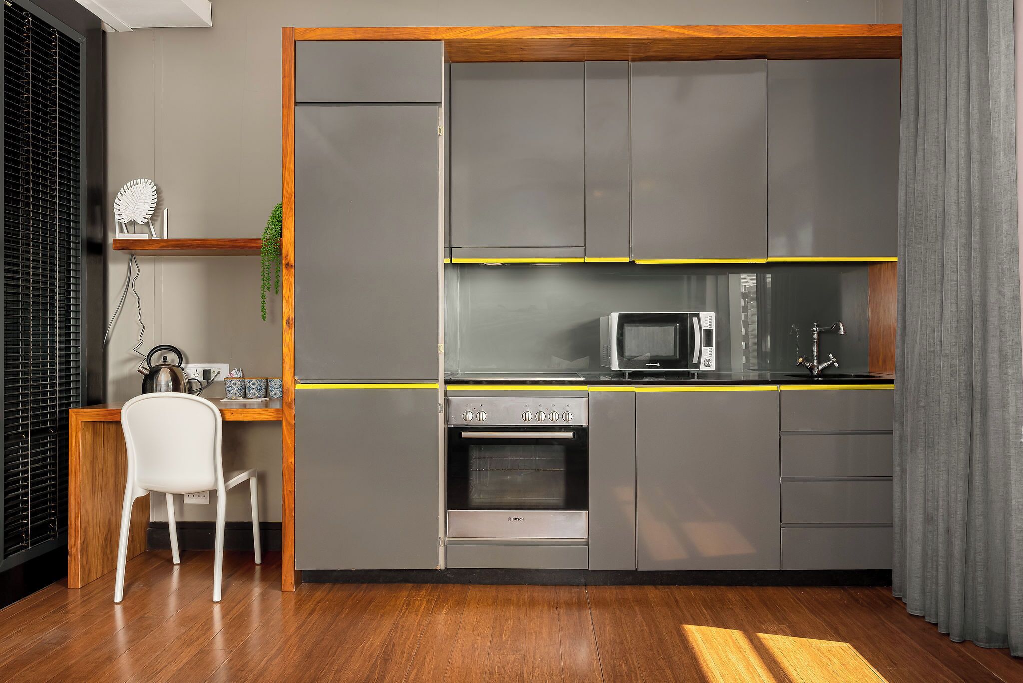 A compact kitchen with grey cabinets, a microwave, and a Bosch oven.