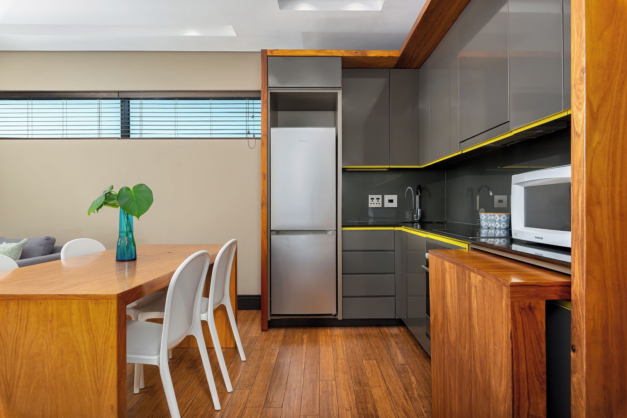 A modern kitchen with a built-in refrigerator, microwave, and wooden cabinetry.