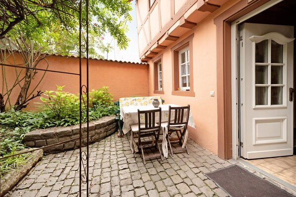 A courtyard with a table and chairs, a door, and a stone wall.
