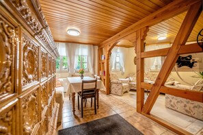 A room with a wooden ceiling, a dining table with chairs, a sofa, and a decorative wall panel.