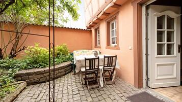Une cour avec une table et des chaises, une porte et un mur en pierre.