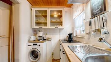 A compact kitchen with a washing machine, a coffee maker, and a sink.