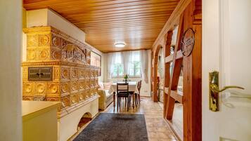 Ein Korridor mit Holzboden, ein Essbereich mit Tisch und Stühlen sowie eine Wand mit aufwendigen Verzierungen.