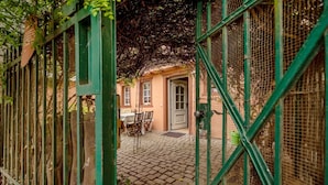 Un patio con suelo empedrado, una mesa con sillas y una puerta que da a un edificio.