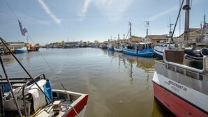 Un puerto con barcos amarrados, cielo despejado y edificios al fondo.
