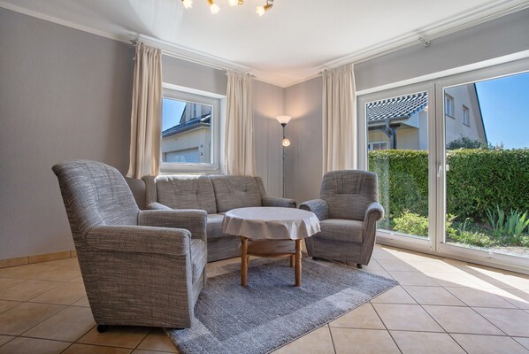 A room with a sofa set, a small table, and a large window with curtains.