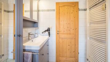 Ein Badezimmer mit Holztür, Waschbecken mit Spiegel und Handtuchhalter.
