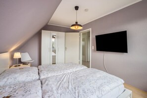 A bedroom with a bed, a TV mounted on the wall, a bedside lamp, and a wardrobe. - Apartment 'Ferienwohnung Krempermoor' with Shared Terrace and Wi-Fi (Krempermoor)