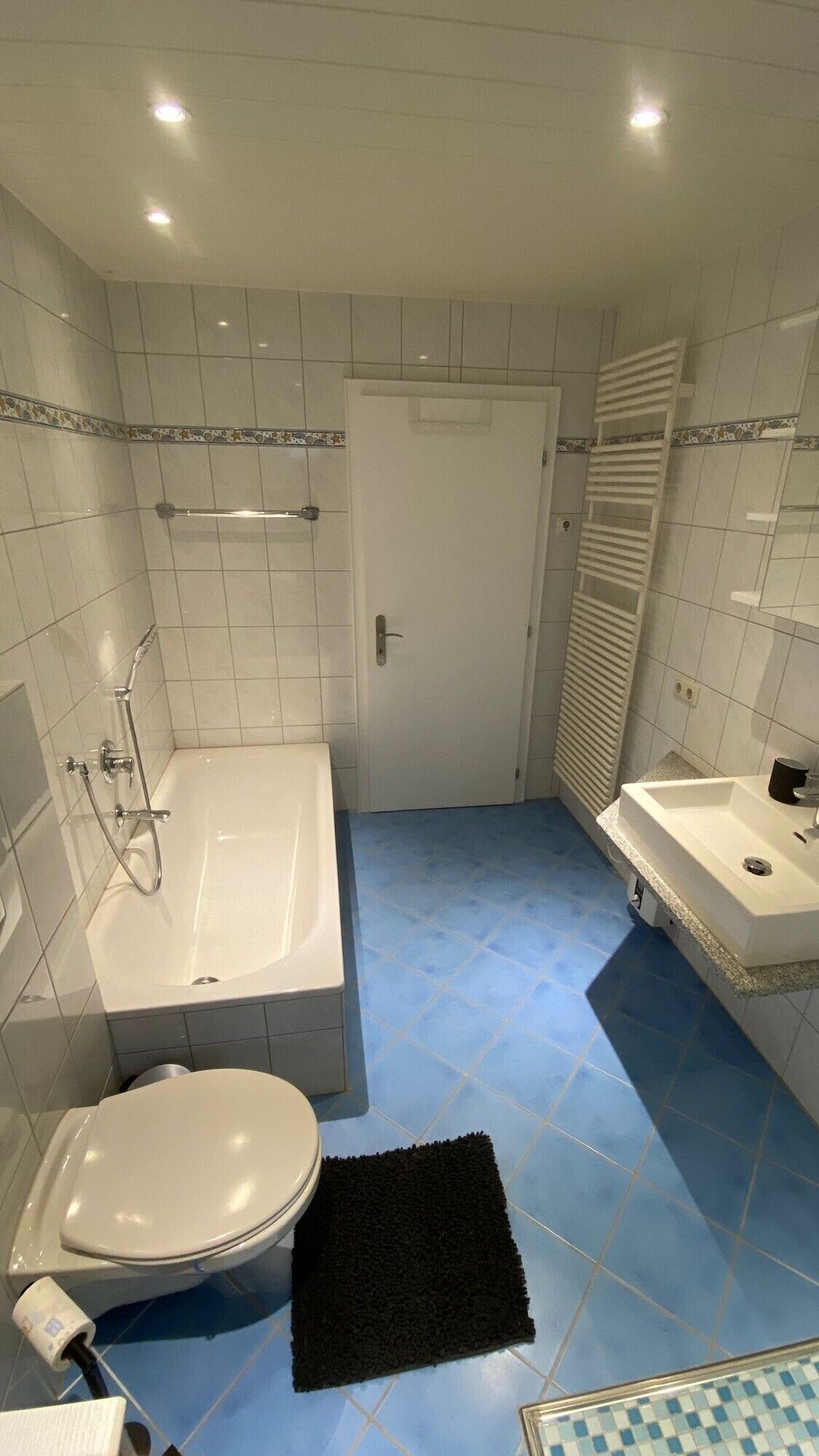 Un bagno con vasca, water, lavandino e portasciugamani.