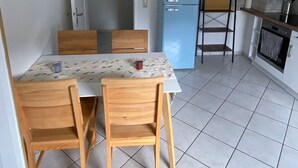 A compact kitchen with a dining table and chairs, a blue refrigerator, and a tiled floor. - Apartment 'Am Sonnenberg' with Private Terrace and Wi-Fi (Reichelsheim (Odenwald))