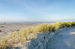 Una playa con dunas de arena y cielo despejado.