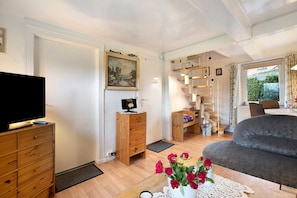 Un salon avec une télévision, des meubles en bois, un canapé et un tableau accroché au mur.