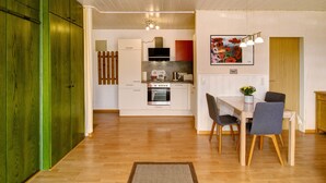 Uma cozinha moderna com armários brancos, uma mesa de jantar de madeira com cadeiras e piso de madeira.