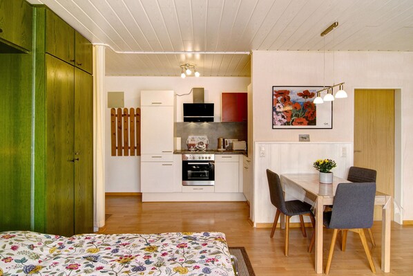 A compact kitchen with white cabinets, a stove, and a dining area with a table and chairs.