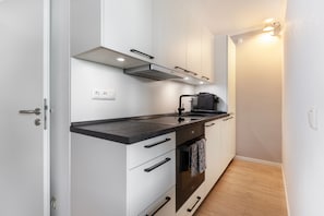 A compact kitchen with a stove, oven, and countertop. - Apartment 'Ostseeresidenz Damp - Ferienwohnung' with Sea View, Balcony and Wi-Fi (Damp)