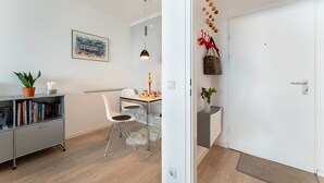 Un interior moderno con comedor, estantería y puerta decorada con un adorno colgante.