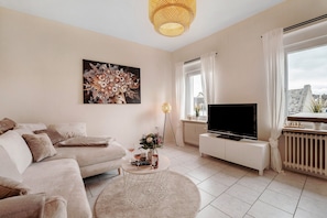 Un salon avec un canapé, une table basse, un téléviseur et une grande fenêtre.