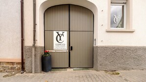 Puertas dobles con un letrero de cosméticos, una ventana con un logotipo y una jardinera con flores.