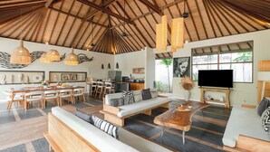 A spacious living area with a high ceiling, a dining area, and a kitchen. - Villa Nikaia by Villa Finder (Seminyak)