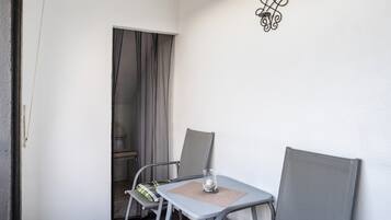 Een kleine kamer met een tafel, twee stoelen, een deur en een wandlamp.