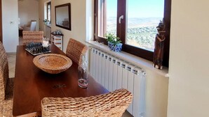A dining area with a wooden table, wicker chairs, a chessboard, and a view of a landscape through a window. - La Vigna di Ranco Agriturismo (Paglieta)