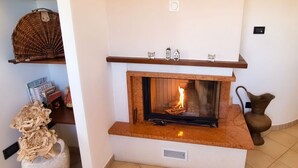 A fireplace with a mantel shelf, a vase with dried flowers, and a tiled floor. - La Vigna di Ranco Agriturismo (Paglieta)