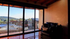 Una habitación con un ventanal grande que da a un balcón con vistas al campo.
