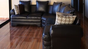 Una sala de estar con un sofá modular, vigas de madera en el techo y un ventanal grande.