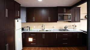 Una cocina moderna con armarios de madera oscura, un lavamanos de acero inoxidable y un microondas.