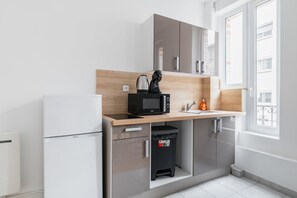 Una cocina moderna equipada con microondas, hervidor de agua y un pequeño cubo de basura.