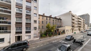 A multi-story residential building with balconies, a street with parked cars, and a clear sky. - Modern 60m² Apartment Near Metro - Paris 12 (Paris)