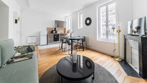 A modern living space with a dining area, kitchen, and a large window providing natural light. - Modern 60m² Apartment Near Metro - Paris 12 (Paris)
