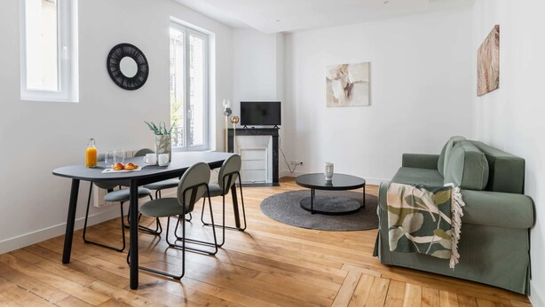 A modern living space with a dining area, a sofa, and a TV. - Modern 60m² Apartment Near Metro - Paris 12 (Paris)