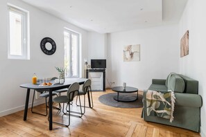 Um espaço de estar moderno com área de jantar, sofá e televisão.