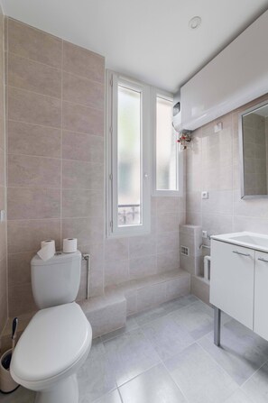 Une salle de bain moderne équipée de toilettes, d’un lavabo et d’une zone douche.