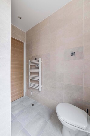 A bathroom with a toilet, a towel rack, and a wooden door.