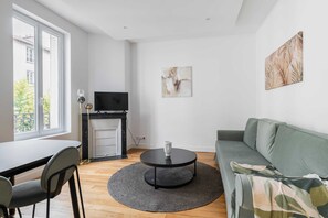 A modern living room with a sofa, a coffee table, a TV, and a fireplace. - Modern 60m² Apartment Near Metro - Paris 12 (Paris)