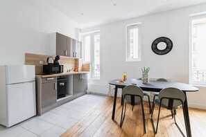 Una cocina moderna con refrigerador, microondas y pileta. Hay un comedor con una mesa y sillas.