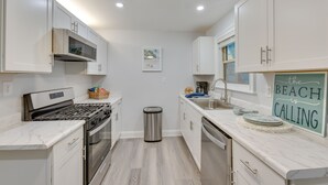 Une cuisine moderne avec des meubles blancs, une cuisinière en acier inoxydable et un évier.