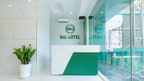 Ein Empfangsbereich mit Wandverkleidung aus weißem Marmor, einer grünen Akzentwand und einer Zimmerpflanze.