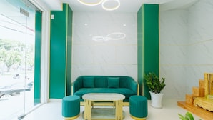 Eine moderne Lobby mit einem petrolfarbenen Sofa, einem runden Couchtisch und passenden Hocker.