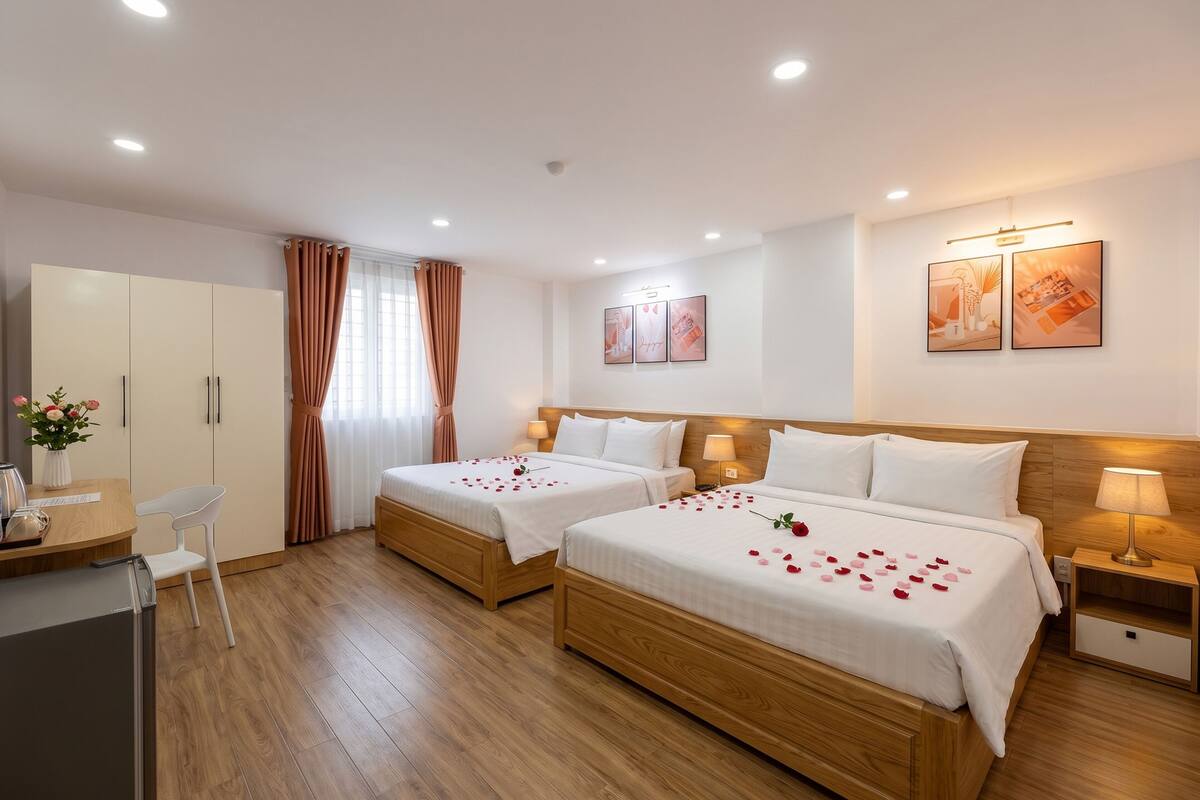 Habitación de hotel con dos camas, un escritorio, una silla, un armario y una ventana con cortinas.