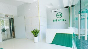 Ein Empfangsbereich mit Glaswand, einer Rezeption und einem Blumentopf.
