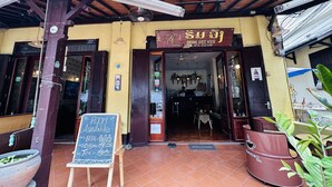 Uma pensão com uma placa indicando disponibilidade de quartos e um cardápio para cerveja, café e chá.