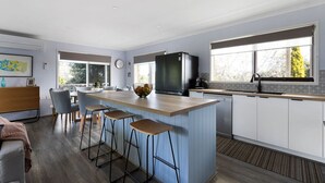 A modern kitchen with a central island, bar stools, a refrigerator, and a dishwasher.