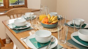 A breakfast table set with bowls, plates, glasses, a pitcher of orange juice, and a bowl of fruit.