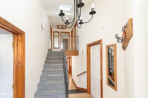 A staircase with a wooden handrail, a black chandelier, and a wooden door on the right. - Beautiful Cottage in Idyllic Somerset Countryside (Shepton Mallet)